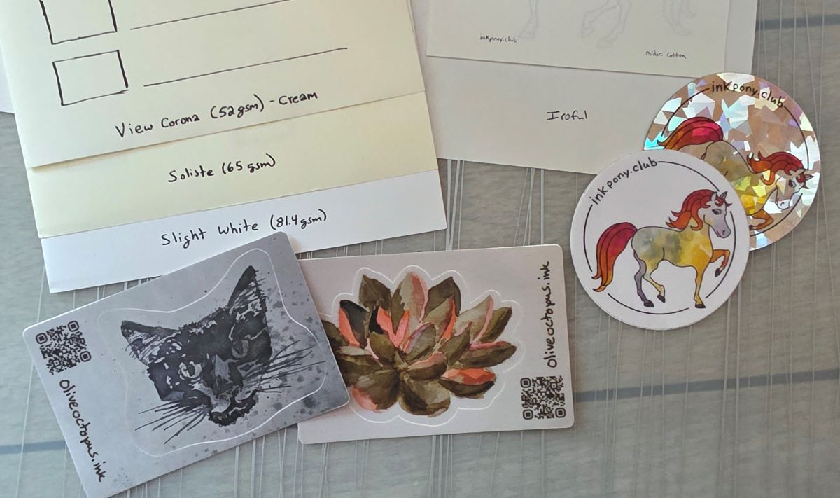 A collection of papers and stickers showing examples of handwritten words converted to digital vectors and printed to label different paper types including View Corona, Soliste, Slight White, and Iroful, and handwritten urls for inkpony.club and oliveoctopus.ink.