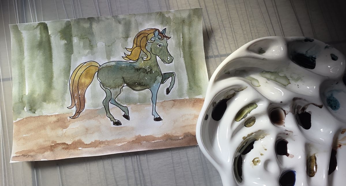 The outline of a pony painted in with fountain pen ink in shades of blue, green, golden yellow, warm brown, next to a ceramic palette filled with ink.