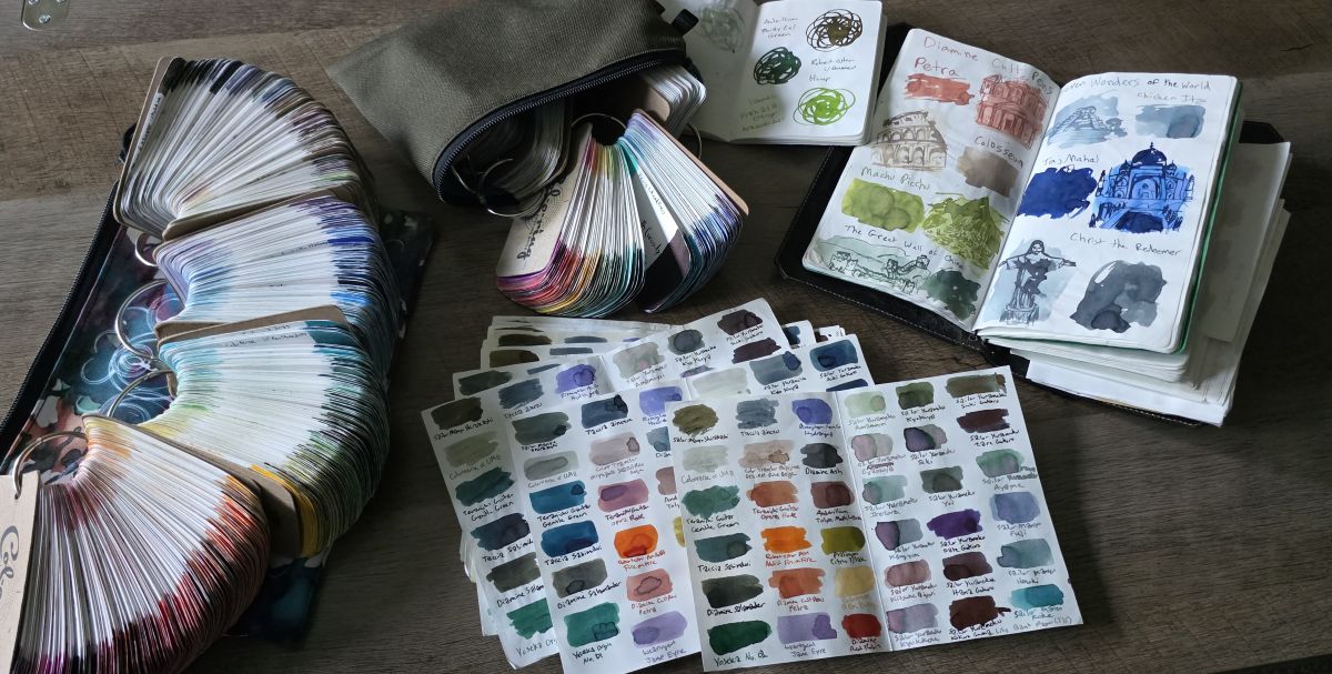 Multiple rings with hundreds of ink swatches on Col-o-ring cards, loose sheets with the same ink swatches on multiple papers, open pocket and A5 slim size notebooks with more ink swatches and sketches.