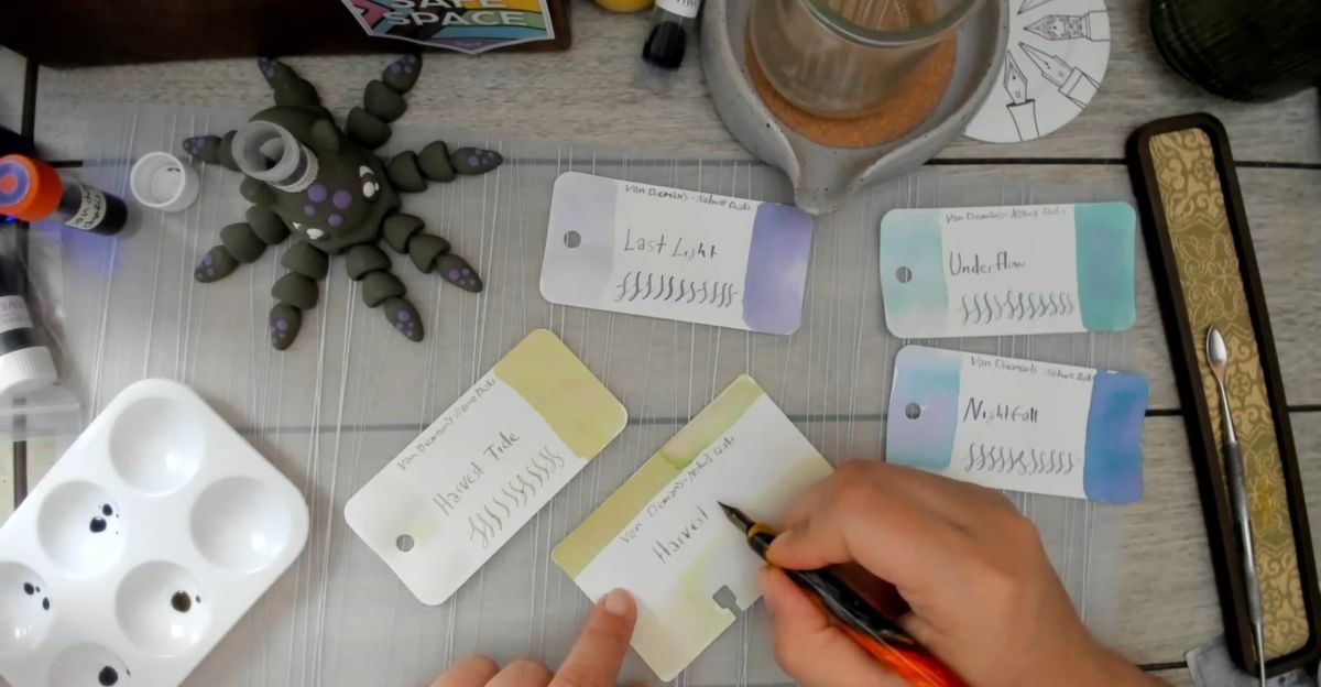 Screenshot of the top-down camera view from a Twitch stream of swatching fountain pen inks from Van Diemans on Col-o-ring and Col-o-dex cards.
