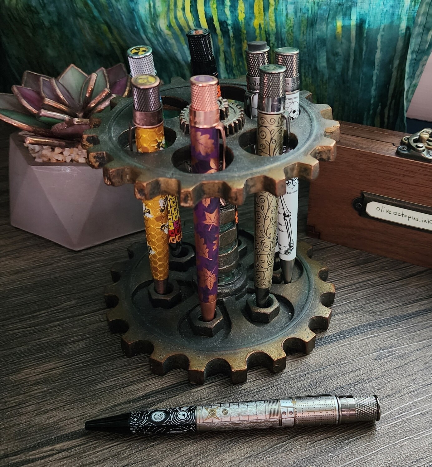 Collection of Retro 51 pens with bees, autumn leaves, the doors of the Palmer in Chicago, Gray's Anatomy, the Periodic Table of Elements, Sleepy Hollow, and Hubble in a gear theme pen holder.