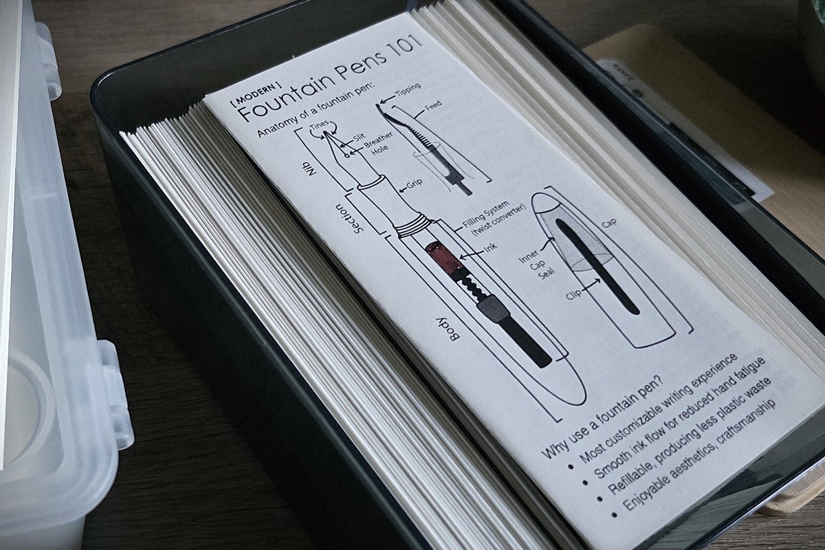 A plastic bin full of folded pamphlets for Fountain Pens 101 with a diagram of a fountain pen on the cover.