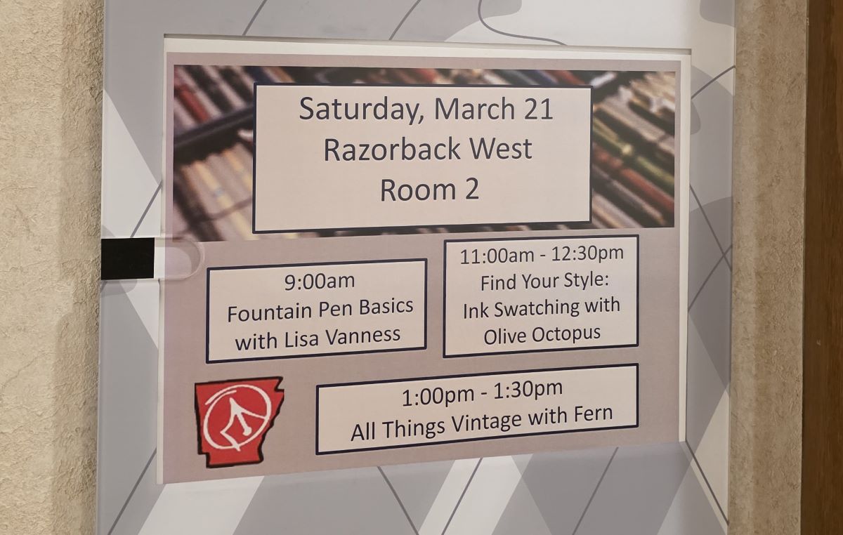A hotel sign for the schedule on Saturday March 21 in the Razorback West Room 2 showing the seminar from 11:00am - 12:30pm Find Your Style: Ink Swatching with Olive Octopus.