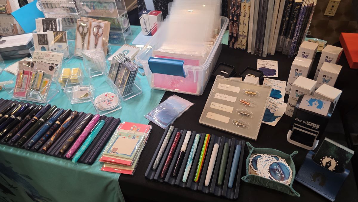 The Stationery Universe table with notebooks, notecards, inks, nib holders, dip nibs, fountain pens, stickers, stationery accessories, and more for sale.