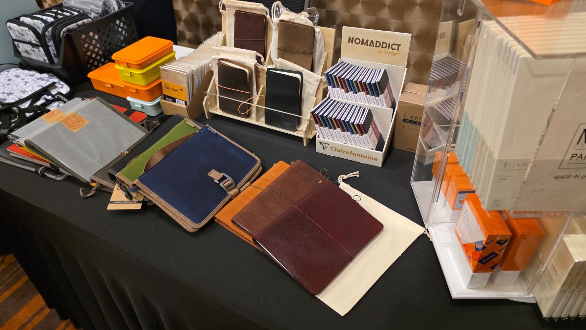 The Gentleman Stationer's table with Midori notebooks, Notsu cards, leather notebook covers, Roterfaden Taschenbegleiters, Rickshaw bags with clouds patterns, steel Toyo boxes, etc.