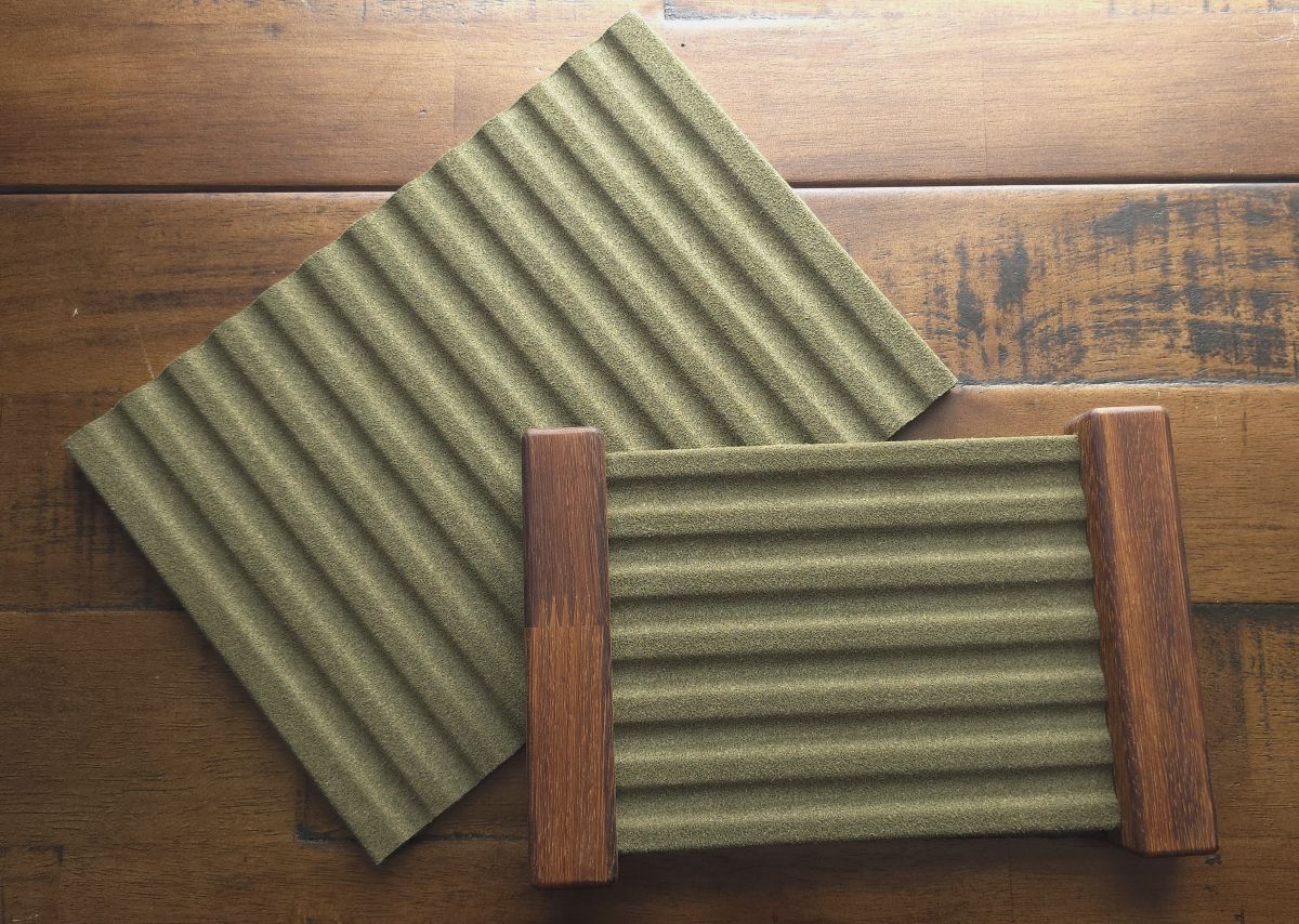 Two dark green NFP pen storage trays including one stand-alone 12 slot tray and a 6 pen tray suspended between wood blocks on each end.