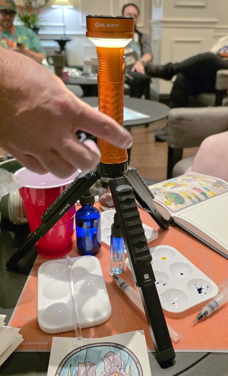 A bright orange flashlight in 'lantern mode' on a tripod illuminating the table.