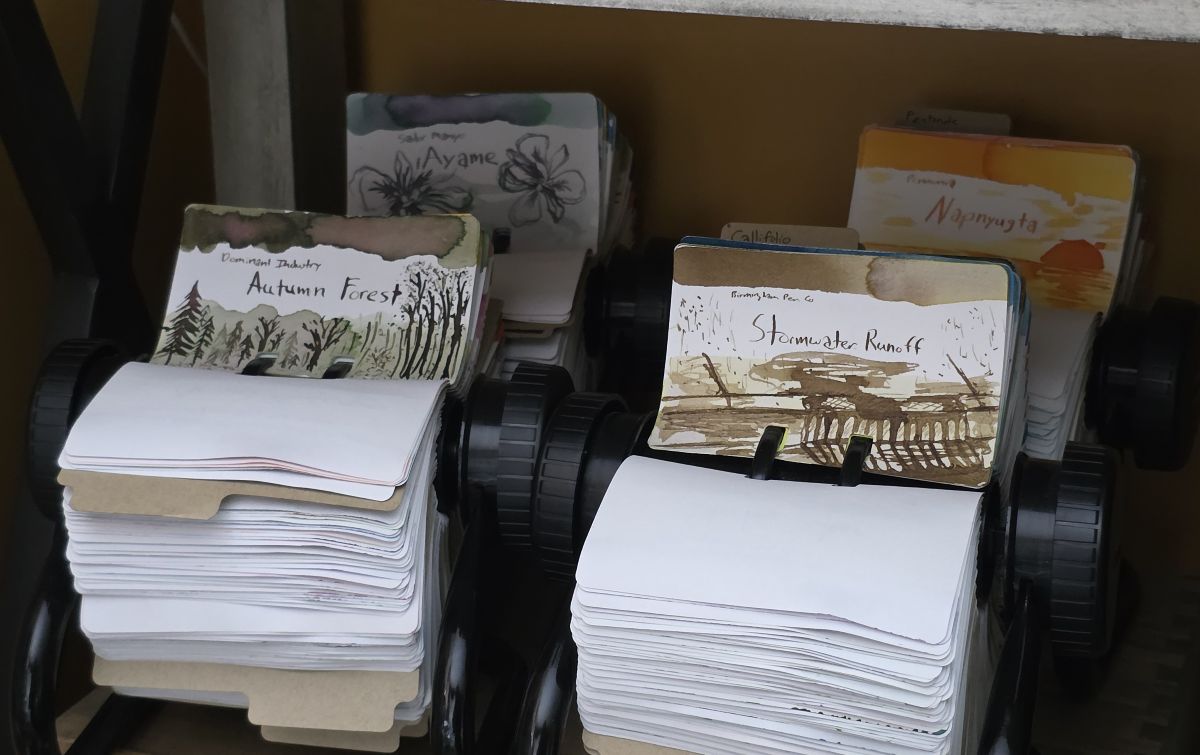 Four circular Rol-o-dex holders on a shelf, each filled with Col-o-dex cards with ink swatches and sketches.