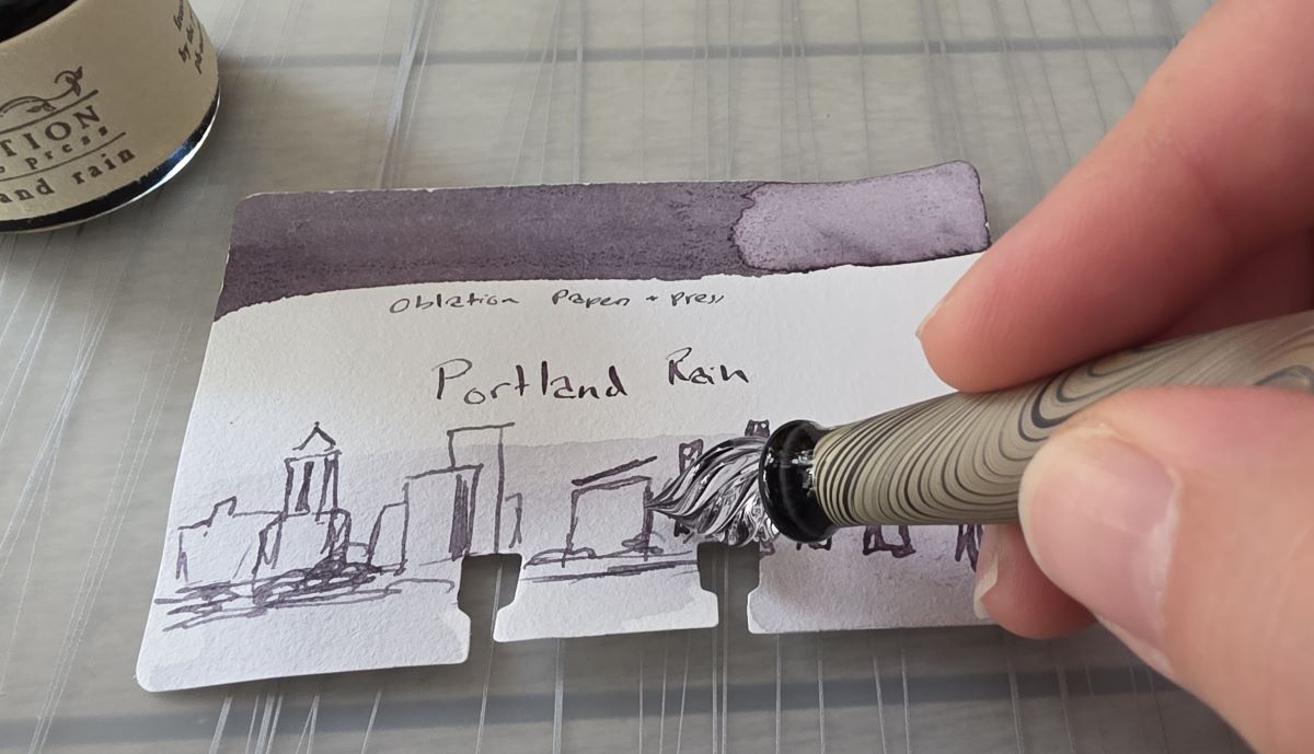 An initial outline sketch of the Portland Oregon skyline being drawn with Portland Rain ink using a glass dip pen.