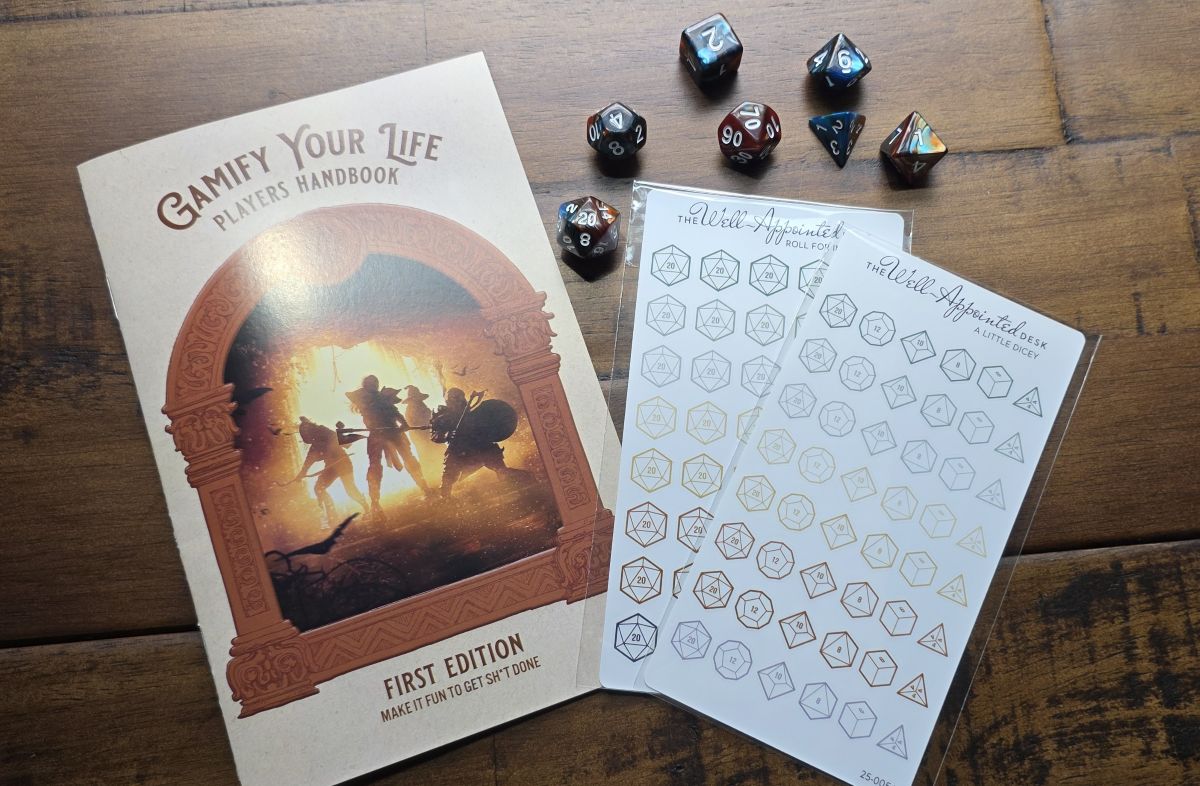A zine called Gamify Your Life Players Handbook, two sheets of stickers of neutral color gaming dice, and a set of 7 gaming dice including a D4, D20, etc. in blue and brown swirled plastic.