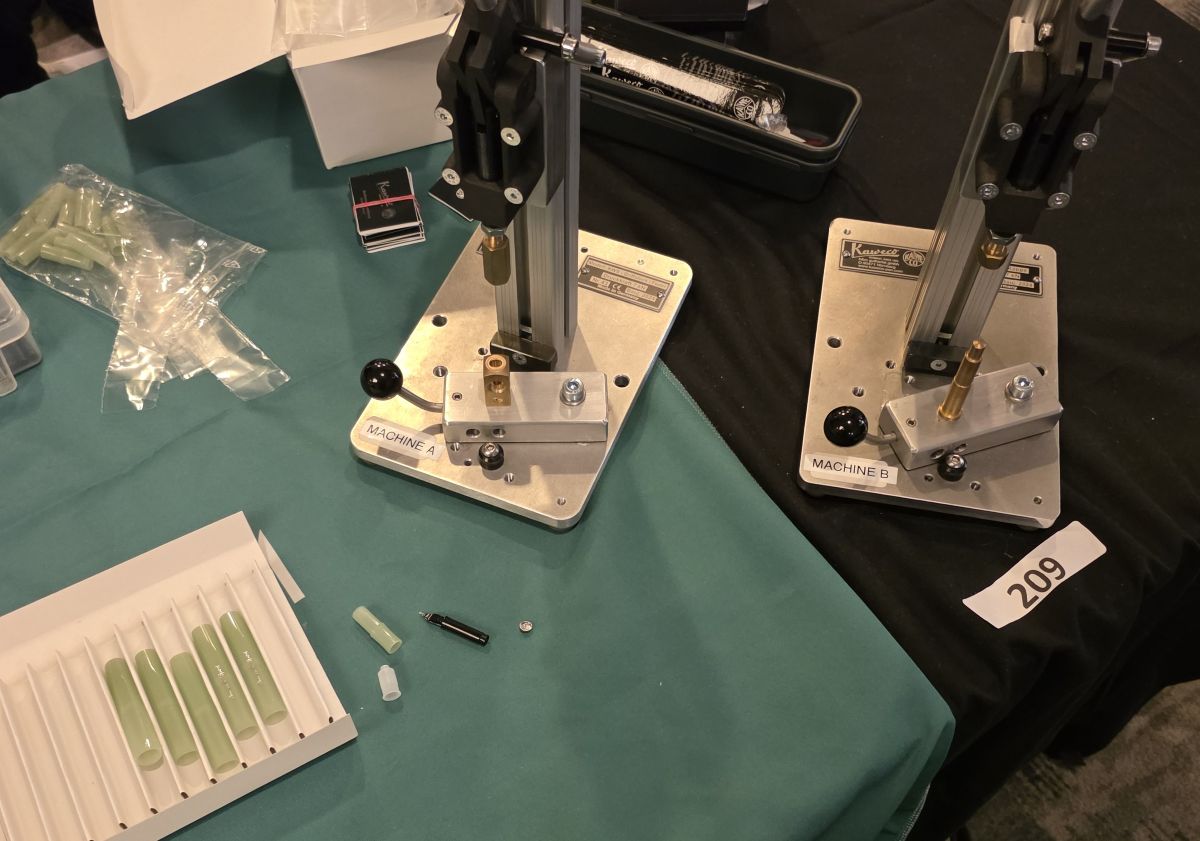 Two hand-operated machines to assemble your own Kaweco sport pen at the Vanness tables and the parts of a DIY glow pen ready to be assembled.
