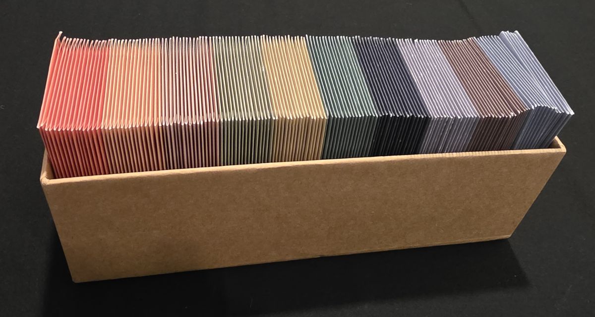 A cardboard box full of small, colorful envelopes.