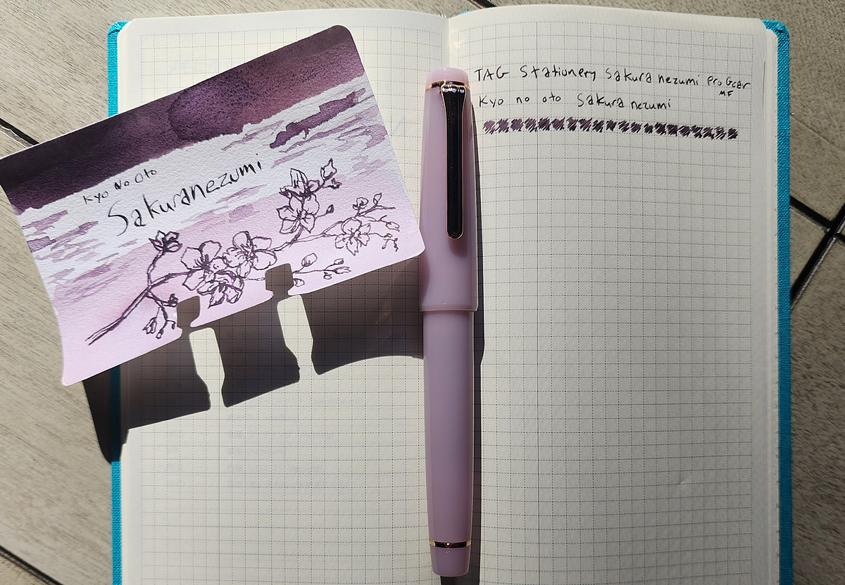 An open Hobonichi Weeks notebook and a Col-o-dex card with a swatch and sketch of a branch of cherry blossoms for Kyo No Oto Sakuranezumi, the TAG Stationery Sakuranezumi Pro Gear pen, and writing sample in the notebook.