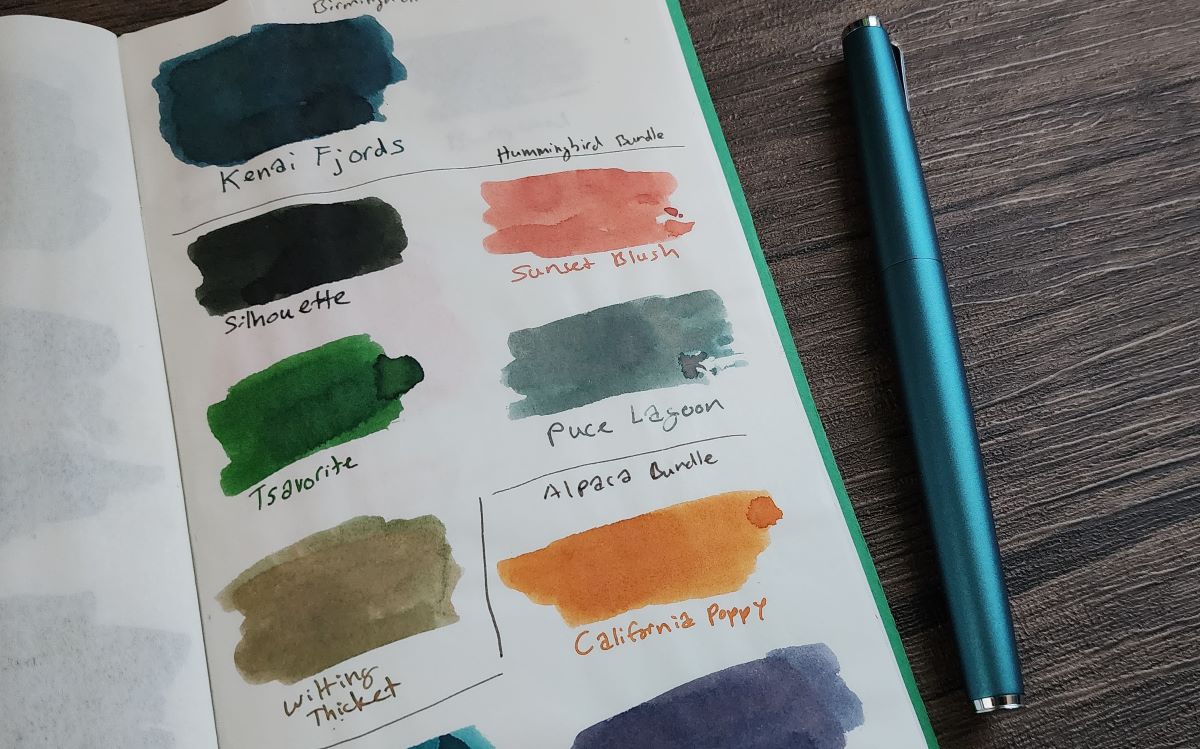 A page of swatches of Birmingham Pen Company inks including Kenai Fjords, Silhouette, Sunset Blush, Tsavorite, Puce Lagoon, Wilting Ticket, and California Poppy. Puce Lagoon looks like a teal gray with hints of pink and purple shades.