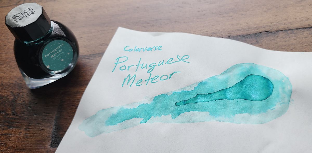 A 15ml 'comet' shaped Colorverse ink bottle for Portuguese Meteor, a vibrant blue-green with shimmer next to a page with the ink name and a drawing of a glowing comet flying through the sky.