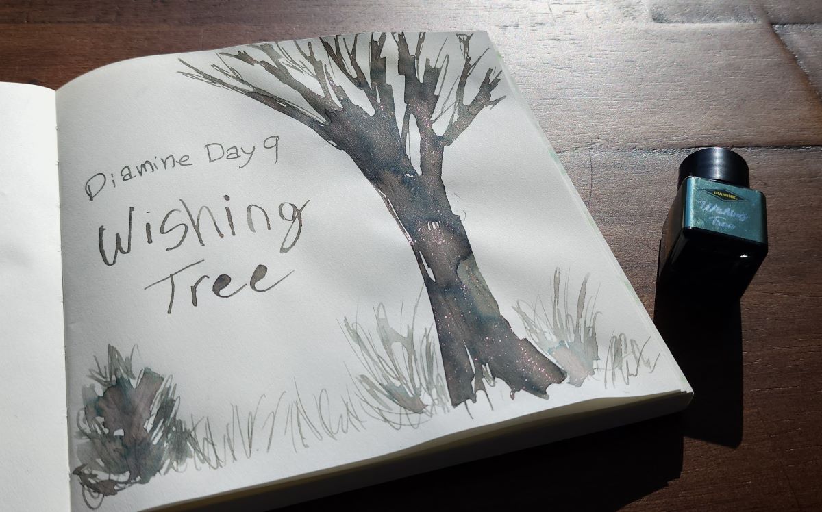 A simple ink painting of a bare tree with Diamine Day 9 Wishing Tree ink, a gray brown with hints of pink and dark blue shading and chameleon shimmer that looks pink at the current angle, next to the small square bottle of ink from the Diamine Inkvent Calendar.