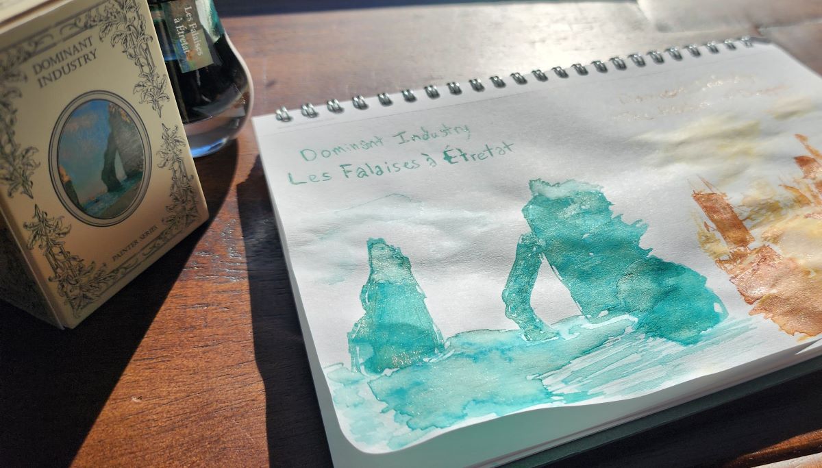 Bottle of Dominant Industry Les Falaises à Étretat ink and angled close-up of a sketch based on the artwork inspiration for the ink, showing more of the multi-color shimmer shining in the rocky cliffs and water.