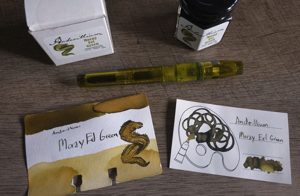 Small jam jar ink bottle of rich yellow green Anderillium Moray Eel Green fountain pen ink next to a translucent yellow-green Franklin-Christoph P46 fountain pen, Col-o-dex swatch card with sketch of an eel, and Iroful swatch card.