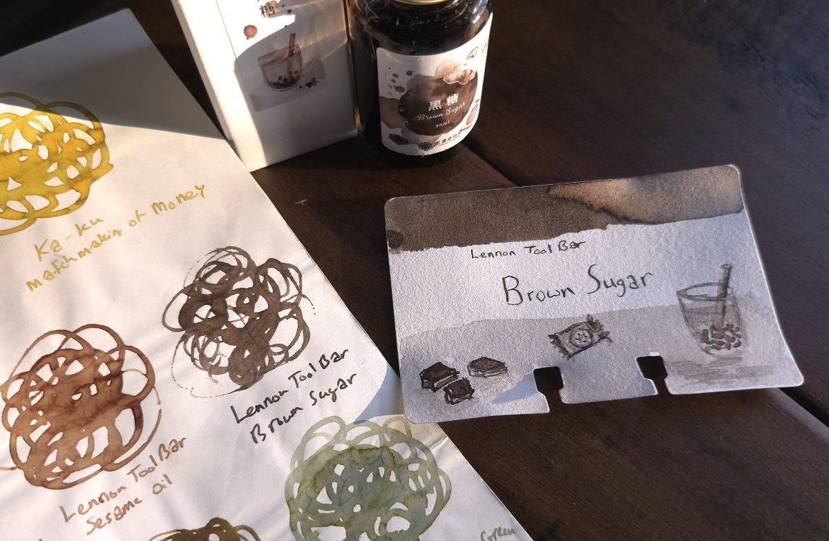 A page of swirled ink swatches next to a bottle of Lennon Tool Bar Brown Sugar and a swatch card for the gray brown ink.