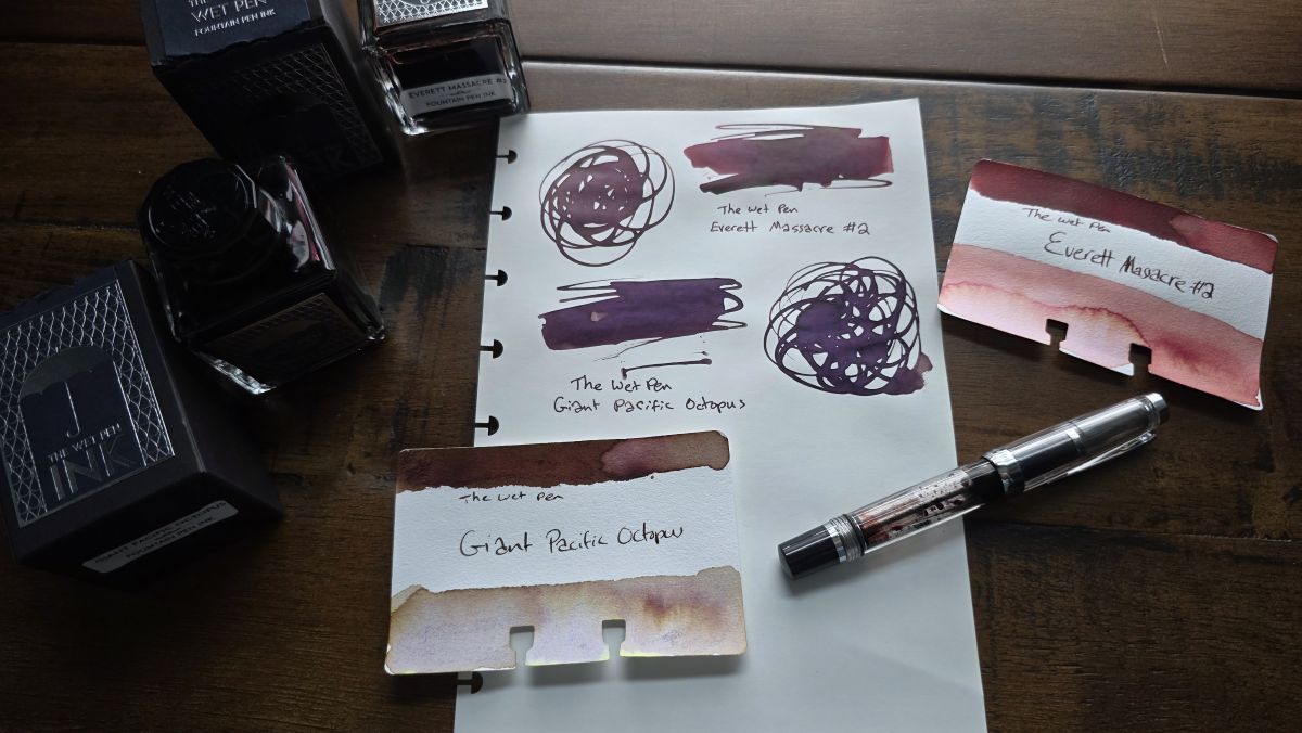A page and Col-o-dex cards with swatches of The Wet Pen Everett Massacre #2 and Giant Pacific Octopus next to the glass bottles of the inks, and a TWSBI Vac Mini filled with the dark red ink.