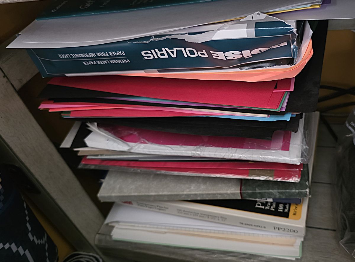 A five-shelf paper sorter on a shelf filled with a variety of papers including printer paper, color paper, photo paper, notebook paper, resume paper, etc.