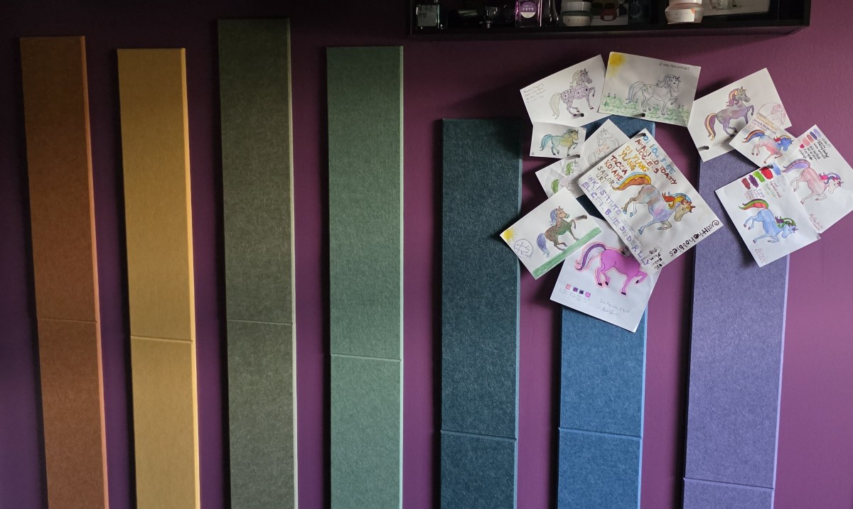 Vertical felt panel strips in orange, yellow, yellow green, sage green, dark blue green, blue, and dusty purple, with painted and colored in ink ponies displayed at the top of the blue and purple panels.