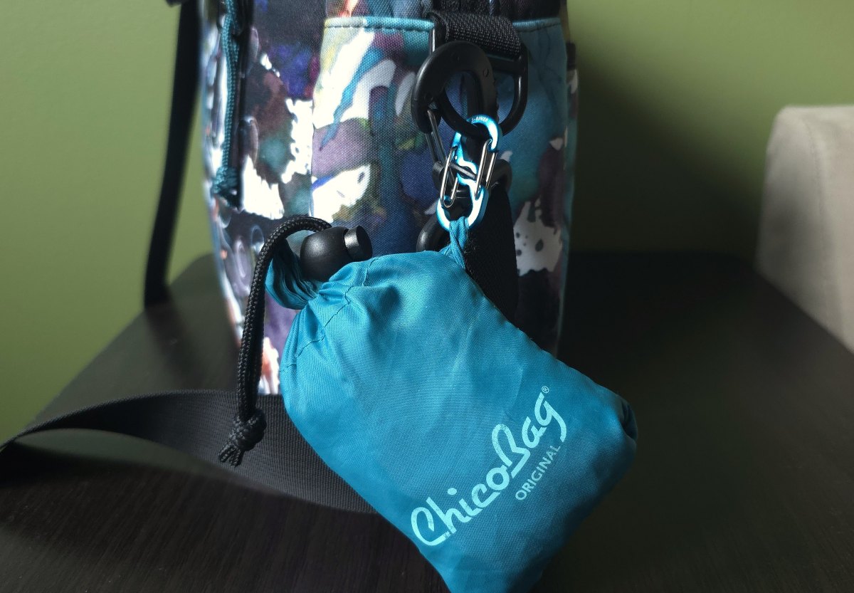 A reusable bag tucked into a pouch and clipped to the shoulder strap ring of a Rickshaw Bonzai bag.