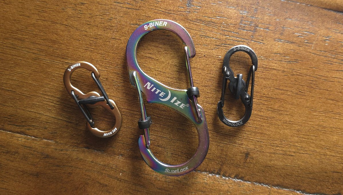 Two small Nite Ize S-Biner clips with a single center twist locking mechanism that prevents both sides from opening, and one larger S-Biner clip with slide lock mechanisms on each end that lock that side from opening.