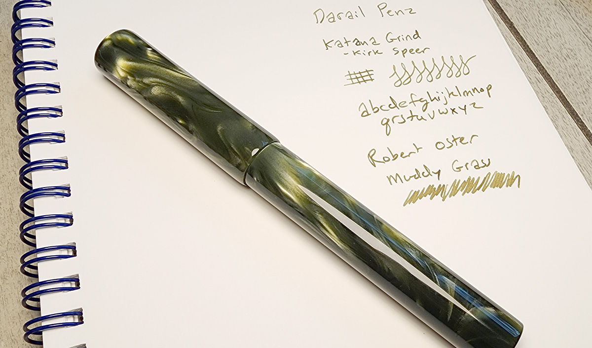 A very chatoyant gray green turned fountain pen with simple lines and glossy finish.