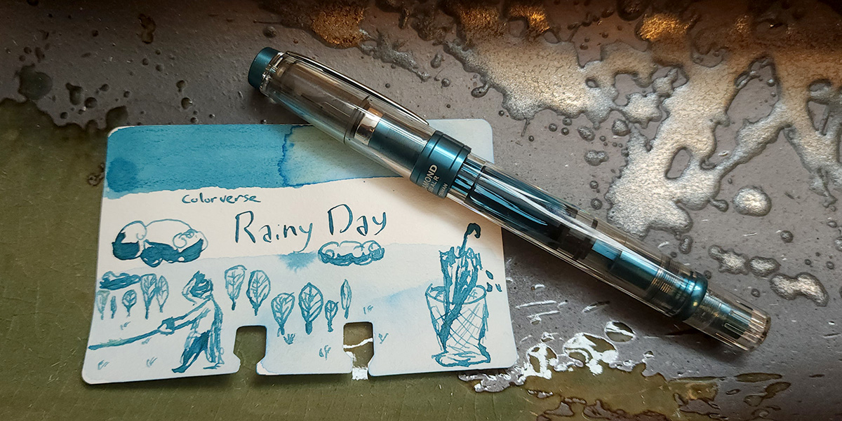 A TWSBI 580 Diamond fountain pen in Prussian blue, a clear body and cap with metallic dark teal accents and piston filling system.