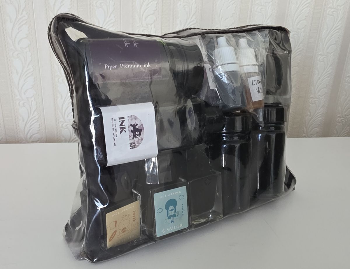 Clear quart size toiletries bag packed with bottles of fountain pen ink.
