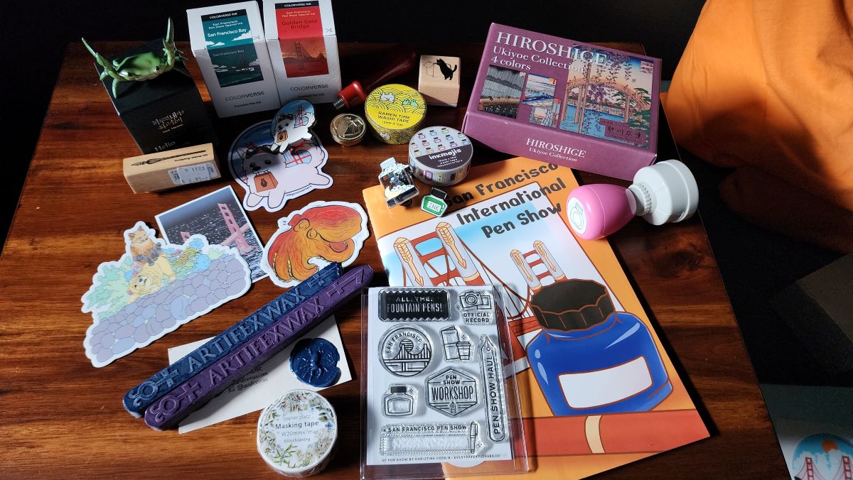 Group of stationery items including inks, stamps, sealing wax, stickers, washi, pen crab holder, pins, sticker book.