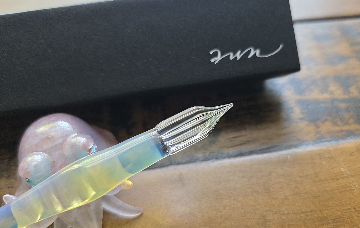 Closeup of yellow and blue glass dip nib pen with broad tip made by Glass Studio Aun.