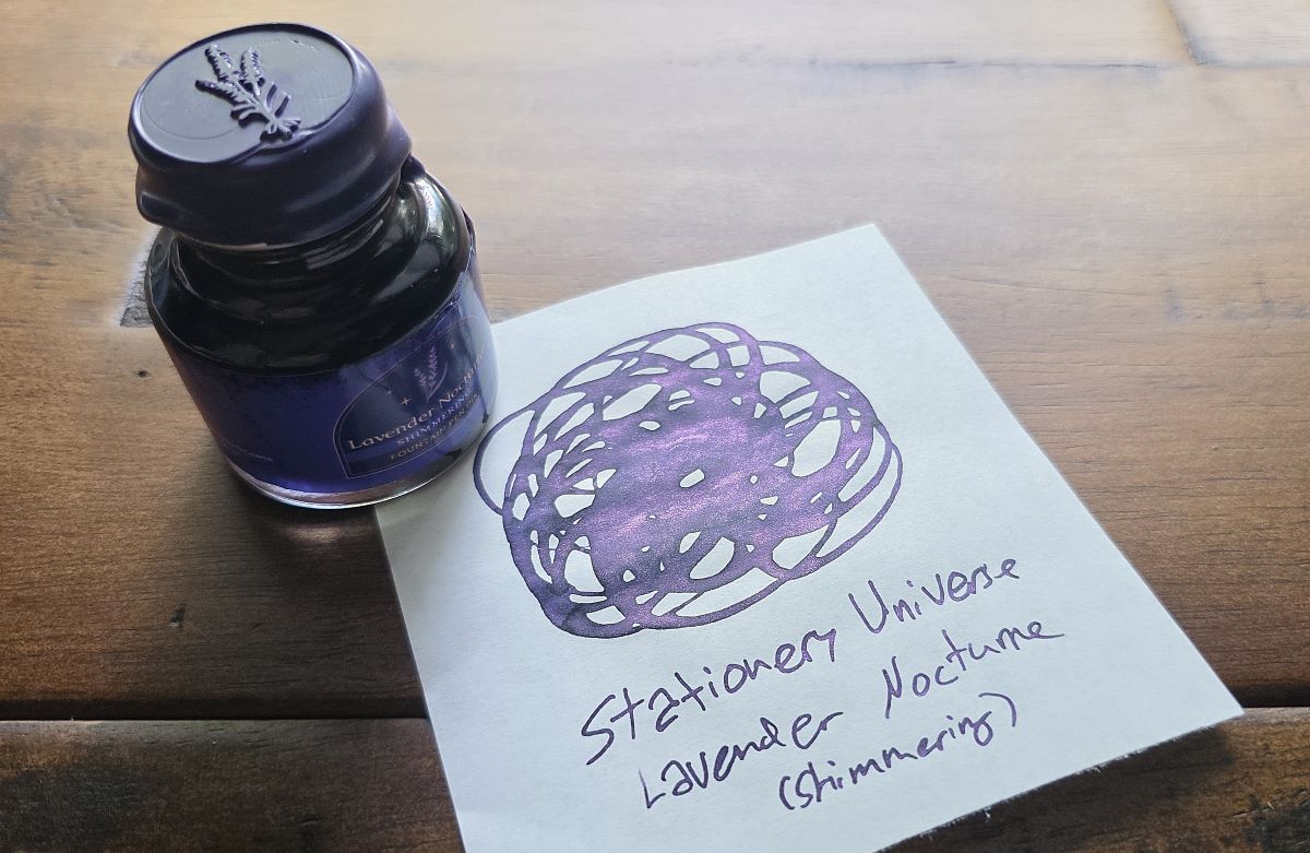 Bottle with wax seal lid and swatch of Stationery Universe Lavender Nocturne shimmer ink, a dark purple with pink shimmer.