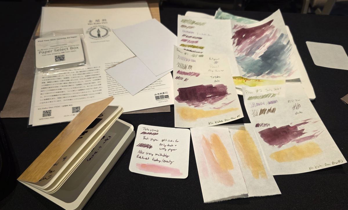 Looseleaf papers, sample papers with writing and ink tests, pocket notebook on desk during paper seminar.