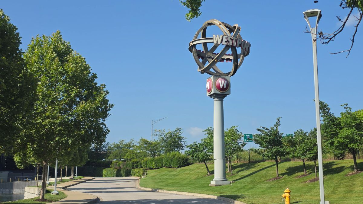 A tall sign where four criss-crossing rings make a ball shape on top of a pole and the name Westport is on both sides of the ball.