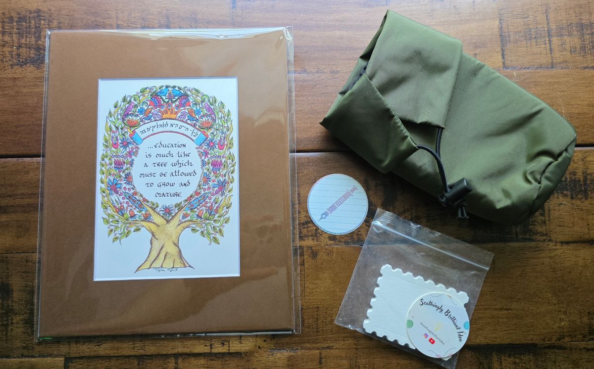 A matted piece of art with a quote about education, a green Nock pen case, Pen Addict sticker, stamp style watercolor paper and sticker from Scathingly Brilliant Idea.