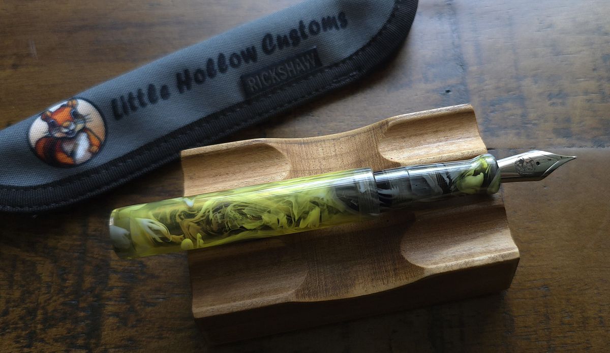 Uncapped turned resin fountain pen showing the logo on the nib and the cap posted using the same set of threads in the middle of the pen.