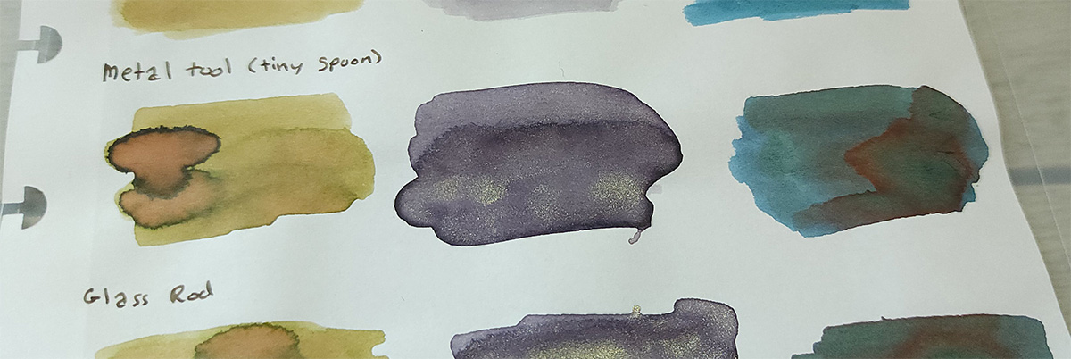 Ink swatches of Sailor 280 with a pale green and a bloom of pinkish hue with dark edges, Colorverse Iris Nebula with dark edges and concentrations of champagne color shimmer, and Taccia Sabimidori with shading blues and greens and red sheen along the edges of the pooled area.