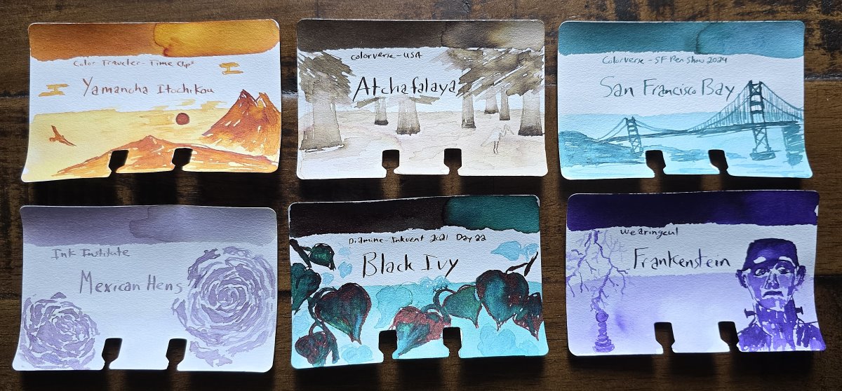 Six Col-o-dex ink swatch cards with sketches including Color Traveler Yamancha Itochikou with sketch of a mountain sunset, Colorverse Atchafalaya with sketch of a swamp, Colorverse San Francisco Bay with sketch of the Golden Gate Bridge, Ink Institute Mexican Hens with sketch of succulent plants, Diamine Black Ivy with sketch of large leaves, and Wearingeul Frankenstein with sketch of lightning and Frankenstein's monster.