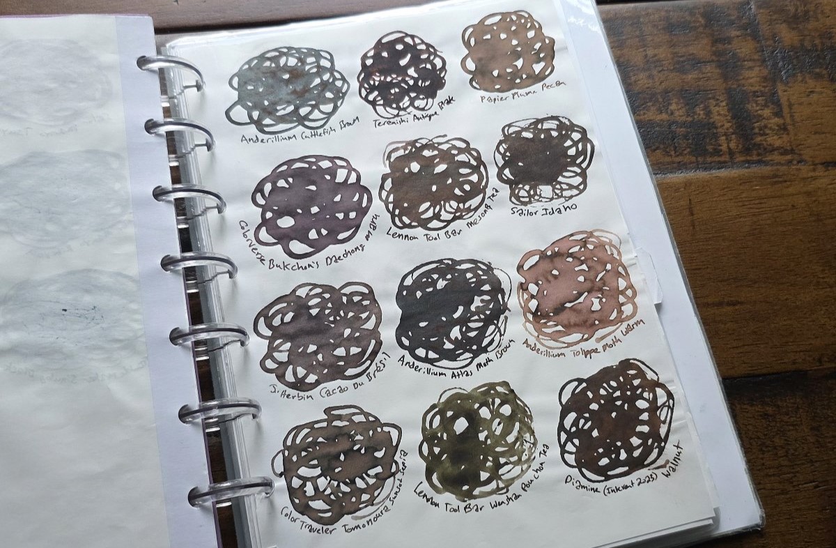 Page in a disc-bound notebook showing 12 swirled swatches of brown fountain pen inks.