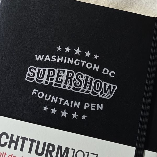 A black A5 Leuchtturm1917 notebook with Washington DC Fountain Pen Supershow logo on the cover.