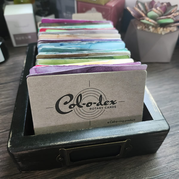 A small wooden tray with col-o-dex cards of ink swatches sorted by color.