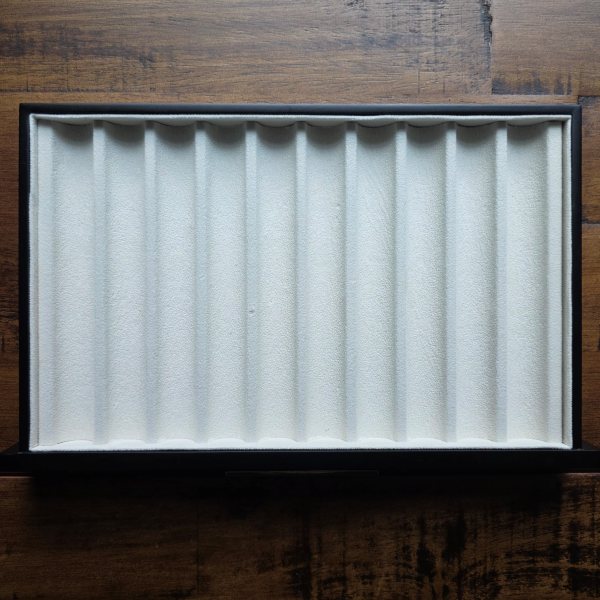 An empty, lined pen tray with ten slots.